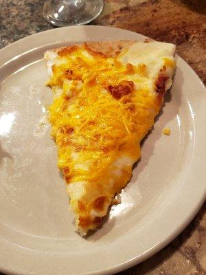 Slice of baked potato pizza. A full layer of mashed potatoes.