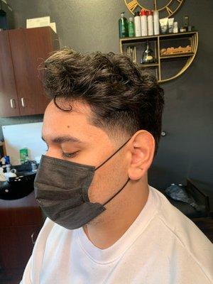 Skin tapered haircut w/ natural curls on top.