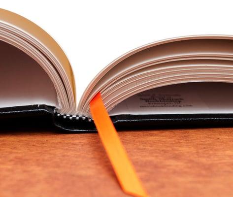 Detail of black bonded leather roundback thesis bookbinding with orange bookmark