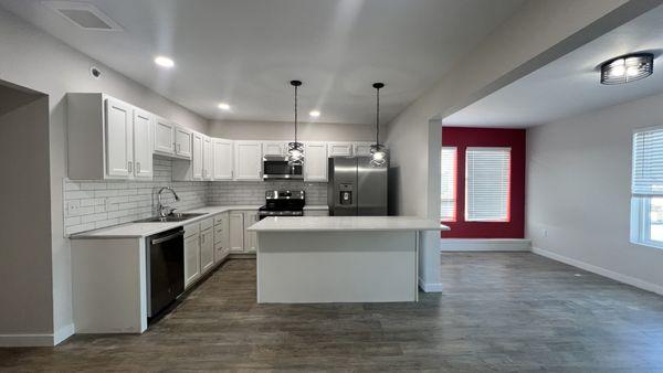 Stylish kitchen with stainless steel appliances, tile backsplash, vinyl plank floors, and an island with storage at Cinema Apartments