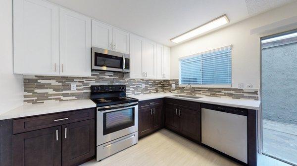 Renovated kitchen with stainless steel appliances, quart countertops, new cabinets, glass backsplash, and wood like plank flooring