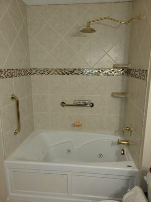 New tub and tile with glass insert, grab bars and corner shelves