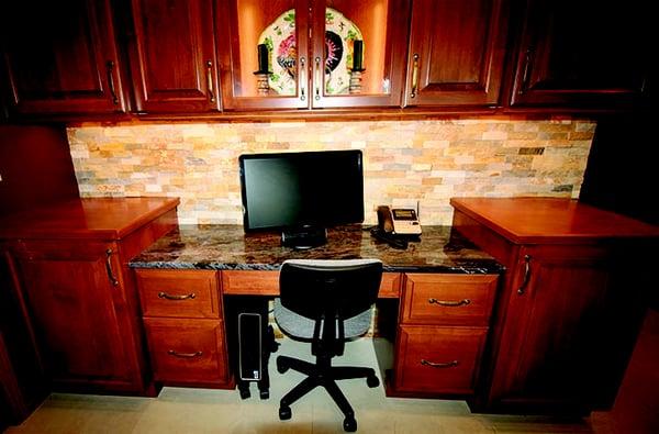 Built-in desk with granite and glass/wood cabinets above.