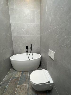 Master Bathroom with floating toilet, free standing tub and walking shower