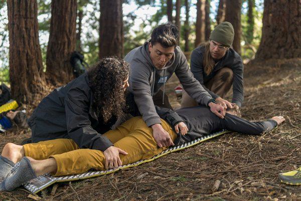 Practicing a three person log roll during a With The Wild Things Wilderness First Aid Class