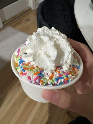 vanilla soft serve with whipped cream and rainbow sprinkles