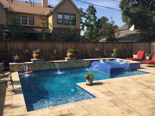 Geometric pool, raised bond beam with shear descents, negative edge dam wall spa raised 18", travertine coping and travertine decking.