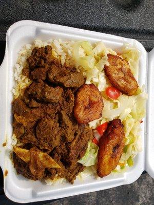 Curry goat, with white rice, plantains and vegetables