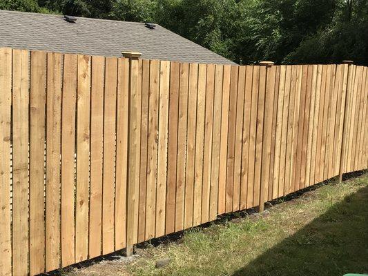 My all cedar fence w/cedar everything- posts, caps, pickets, cross bar thingies :-)  They handled my sloping land well. 1/2" gaps for wind