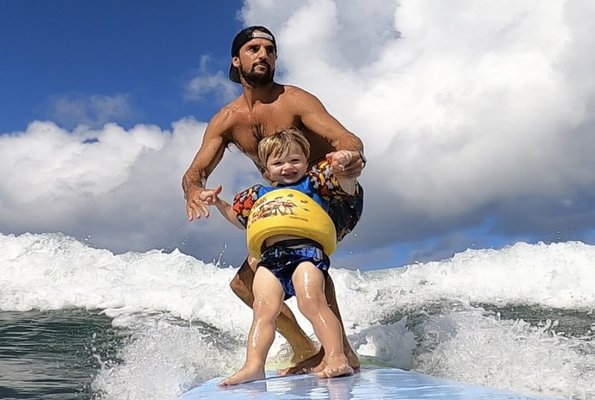 Mike of 808 Surf School surfing with his 2 year old son