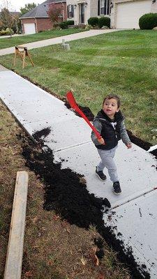 Father and son time backfilling new sidewalk with topsoil