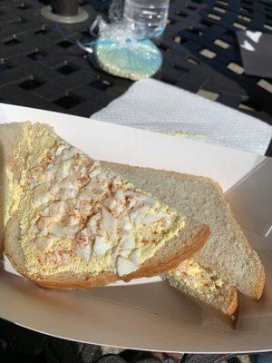 First half of sandwich with smidgen of flavorless curry egg salad, on white stale bread.