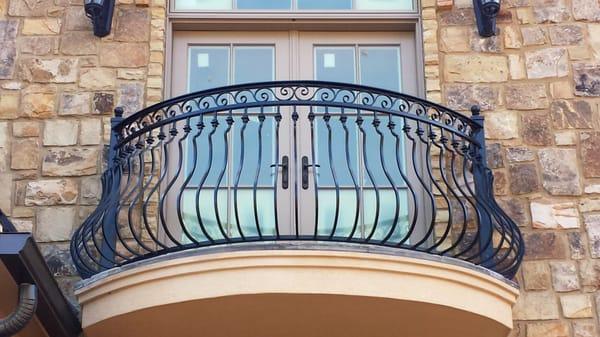 Custom wrought iron balcony railing featuring belly pickets finished with black powder coating