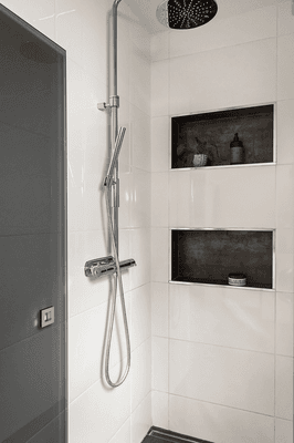 Shower with integrated shelves, black tinted glass doors and invisible drain.