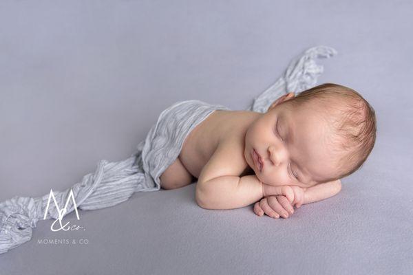 Baby girl covered in wrap on gray blanket