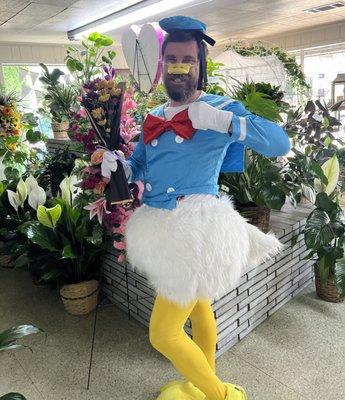 Mitch in humiliating Donald Duck costume posing with flowers.