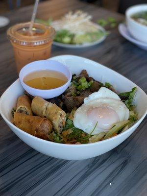 Ig: @eat_with_jeleneeee | Vermicelli bowl with Thit Nuong, egg rolls, and an added egg (Thai tea in the Back)