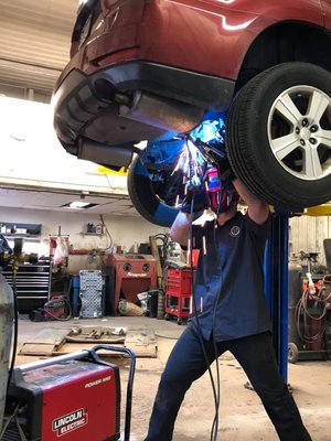 welding a muffler onto a car