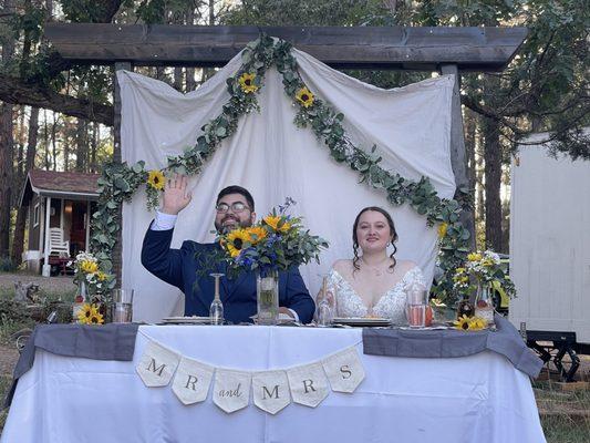 Sweetheart table setup on a little hill so all could see. Rental potty trailer in the background on right and cabin on left.