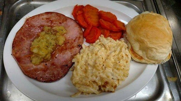 Ham steak dinner with cheesy potatoes, glazed carrots, homemade bun, and a pineapple salsa