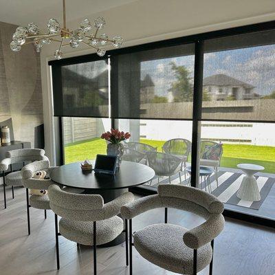 Elegant black solar shades in a modern home on the large sliding door to maintain visibility while cutting back the glare from the table.