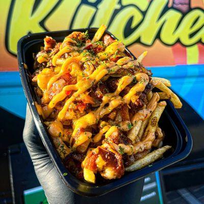 Our Fritay Griot Loaded Fries - Grilled Peppers, Grilled Onions, Chopped Griot, Cheese On A Bed Of Fries And Drizzled With Chipotle Sauce