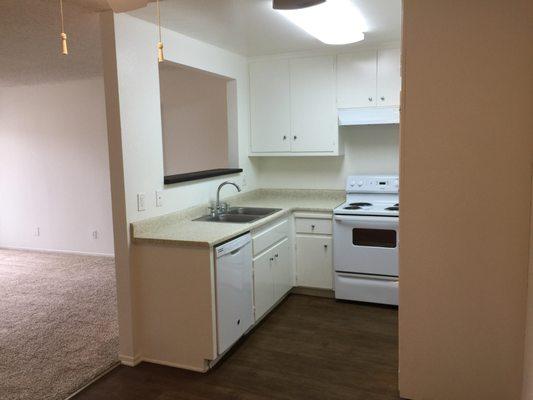 This kitchen has light wood floors and a view to the living room and balcony.