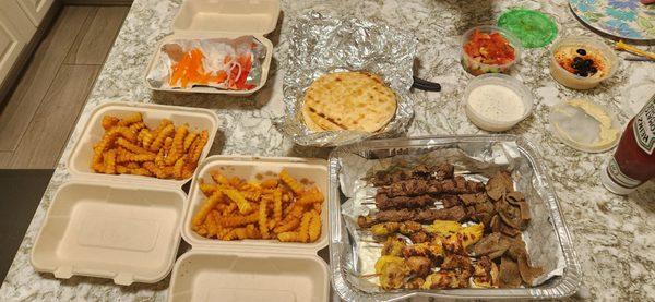 Chicken kabobs, beef kabobs, gyros, pitas, fries, fresh veggies, tzaziki sauce, hummus, baklava. Enough for 4 people!