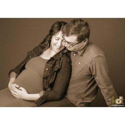 Pregnant couple snuggles in black and white studio portrait, Flagstaff, AZ