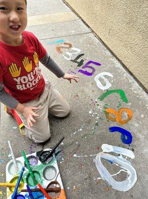 At Mrs. Cabrera's students learn through play. The student practiced his number formation while painting and having having fun outdoors!