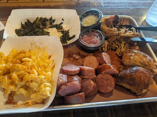 Partially eaten 4 meat & 2 sides combo. Italian Sausage, Kielbasa, Chicken, and Pulled Pork. Collards and Mac & Cheese.