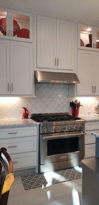 Custom cabinets with cabinet lighting, quartzite countertops, and arabesque.backsplash tile.