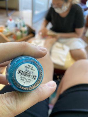 Pedicure in background with fingers holding teal polish, "dance party teal dawn" in foreground.