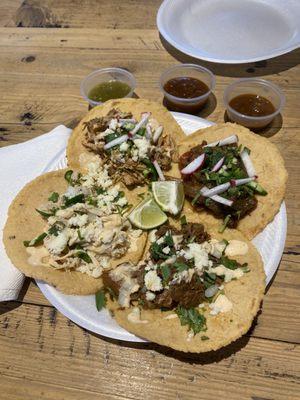 Starting top left (going clockwise): carnitas, vegan tejano, shredded steak, and carnitas. 3 levels of hot sauce.