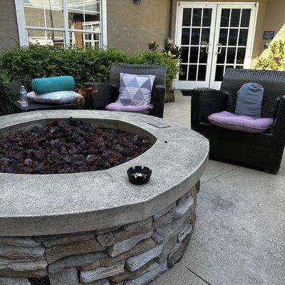 Smoking area with fire pit, propane grill, and outdoor table for dining.