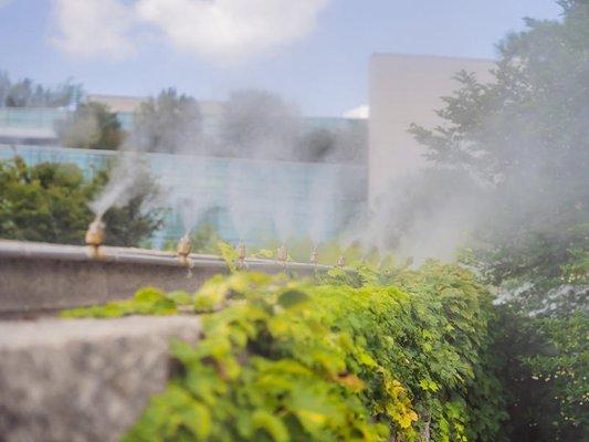 A mosquito misting system on a lawn in front of a business