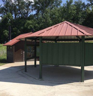 Pavilion (without a table or seating) and privies at the start of the walking path.