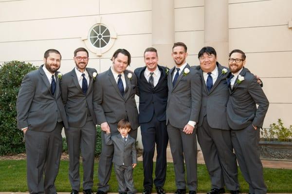 Dark blue suit with a grey tie for the groom/ dark grey suits with a blue tie for the groomsmen.