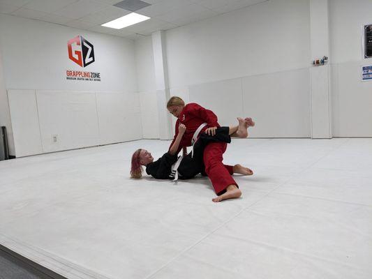 two teens doing Brazilian Jiu-jitsu on a mat in a dojo at Grappling Zone Friendswood