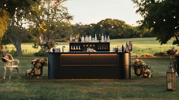 A sleek, modern outdoor bar with stylish lighting and floral decor, ideal for high-profile events and exclusive celebrations.