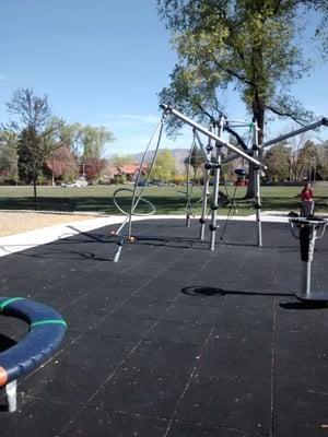 Bigger kid play area with some electronic games. A large grassy area behind the playground.