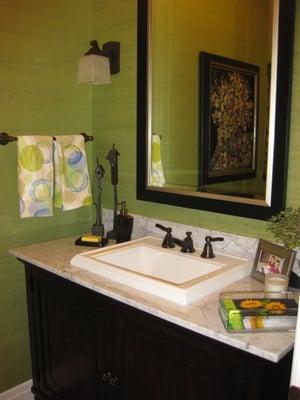 This powder bath has a furniture vanity cabinet with a marble top.