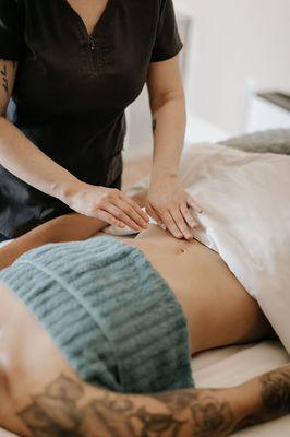 A woman receives Manual Lymphatic Drainage to her abdomen for post-op swelling.