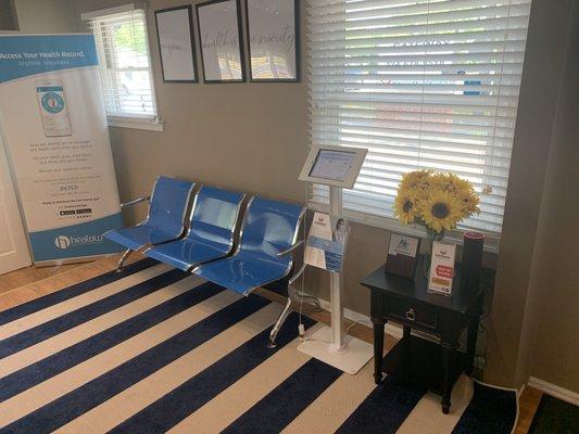 Interior shot showing check-in kiosk, seating, Chamber of Commerce plaque, and Healow banner for online booking