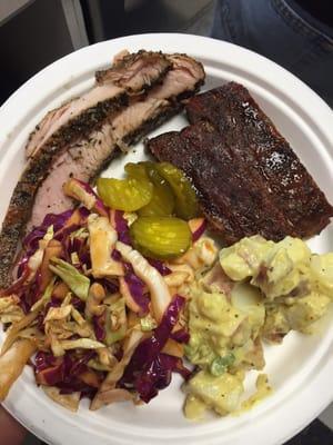 A catered plate with pork ribs, brisket, mustard slaw, potato salad and pickles.