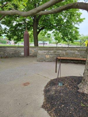 Bell sculpture on tree, with mallet located near the trunk.