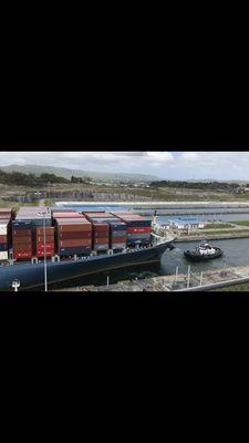 Panamax Container Ship being escorted thru the Panama Canal by a tug boat.