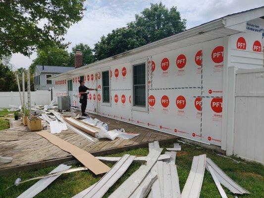 Fanfold insulation being installed over the new house wrap (moisture barrier).