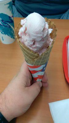 Strawberry ice cream in a waffle cone.