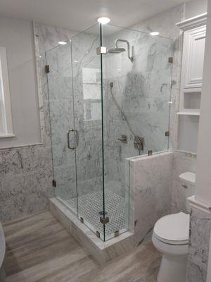 Walk in shower with Calacatta Marble 12X24 tile and a frameless glass shower surround.
The cabinets are by Omega Cabinetry.